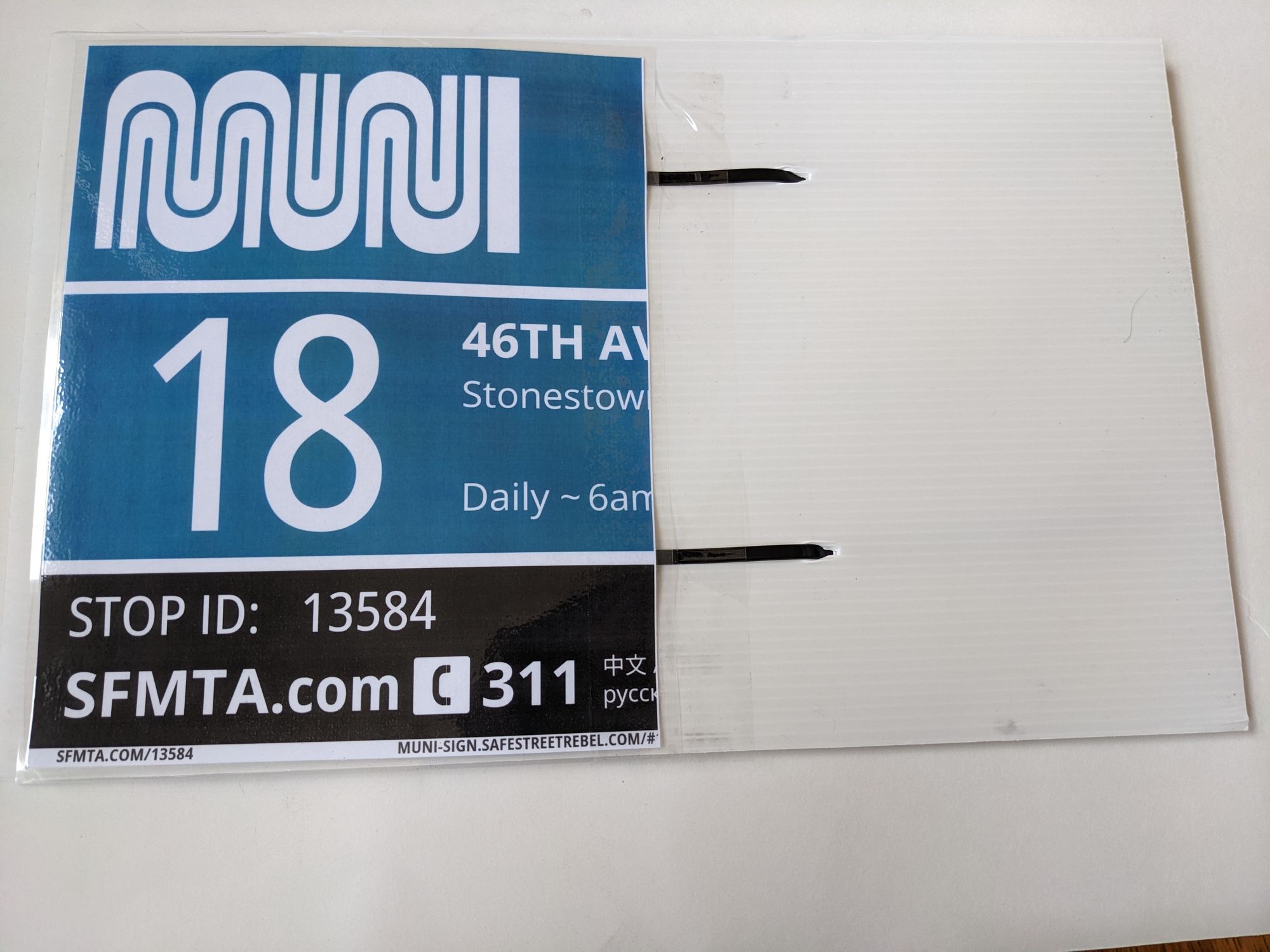 Half of a laminated muni sign has been taped to the reverse side of the sign with the zip ties shown in the previous photo