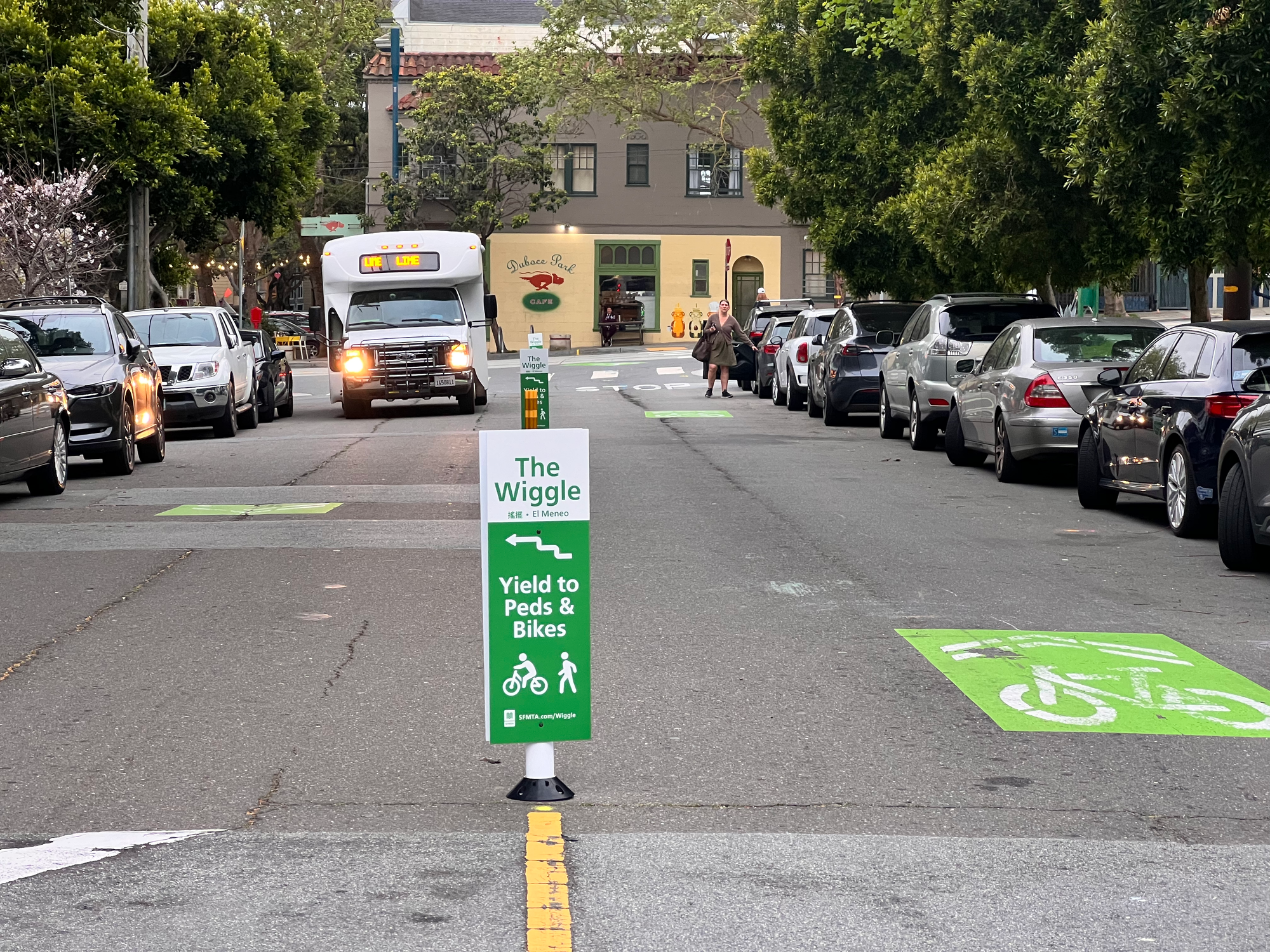 soft hit posts with paddle signs that read "the wiggle: yield to peds and bikes" down the centerline of a street