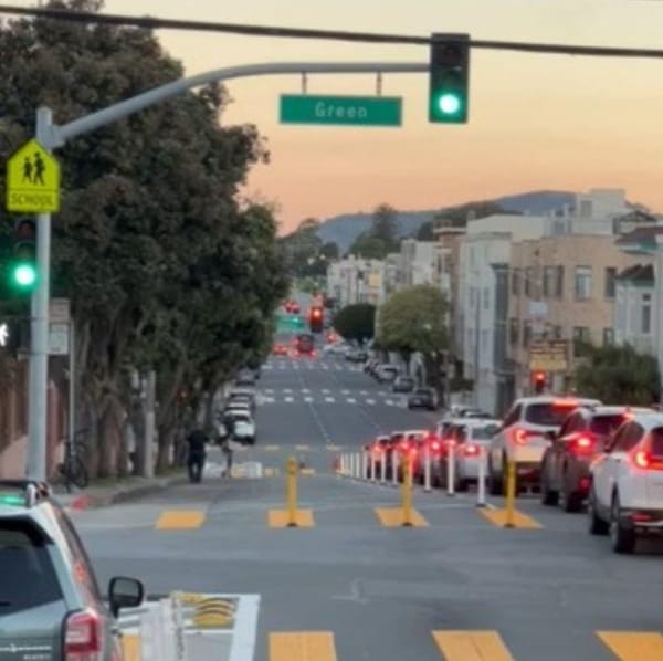 A 3-lane one-way street with flexposts closing off the leftmost lane for a full block