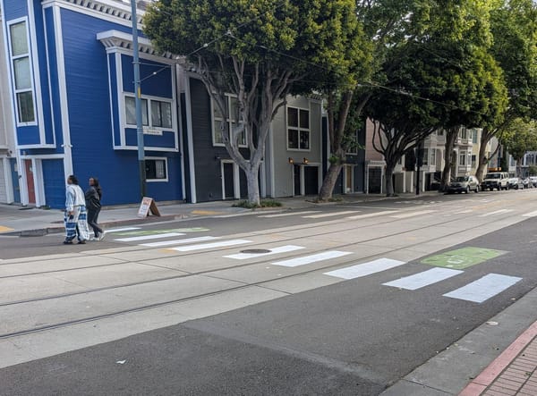 A well painted crosswalk connecting two segments of sidewalk that are directly across the street from each other at an unsignalized intersection